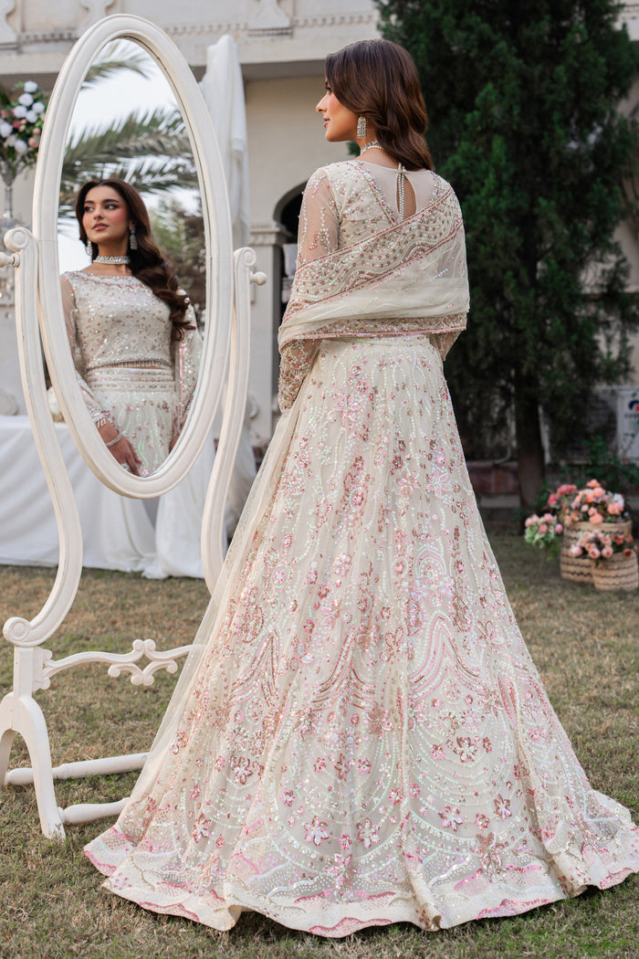 Woman in a floral embroidered outfit standing next to a mirror outdoors.
