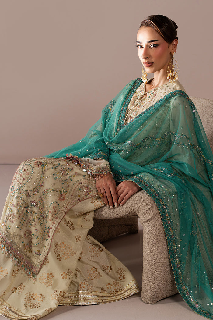 Seated view of Alanah off-white 3-piece outfit showing the embroidered shirt, flared pants and contrast teal Net dupatta.