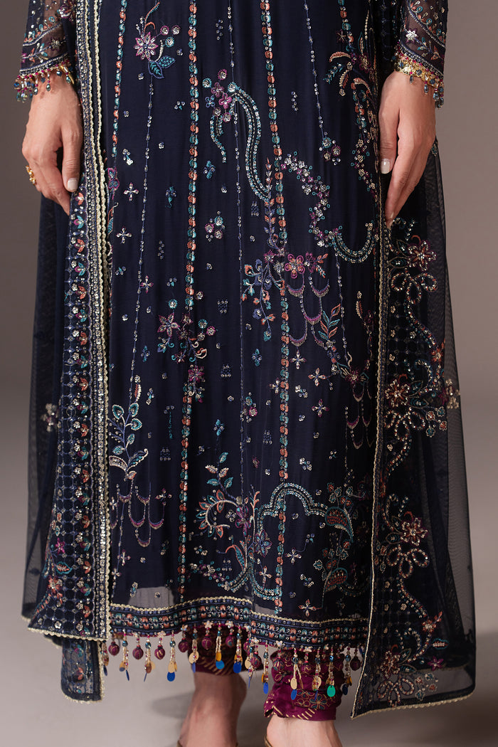 Close-up of Alishma showing machine embroidery, sequins, contrast accents, cutwork and decorative hem details on the navy blue shirt.