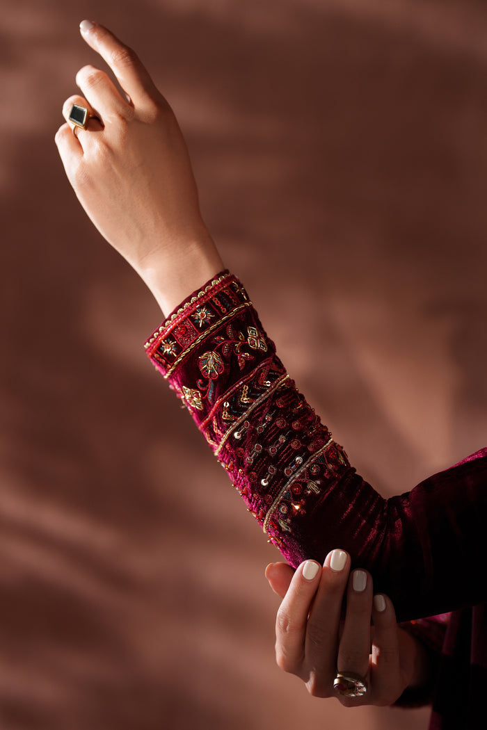 Close-up of a hand wearing a red embroidered arm sleeve against a brown background