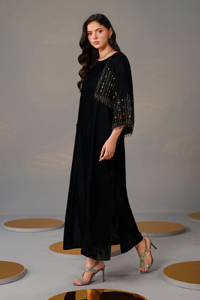 Woman wearing a black dress with beaded sleeves on a gray background
