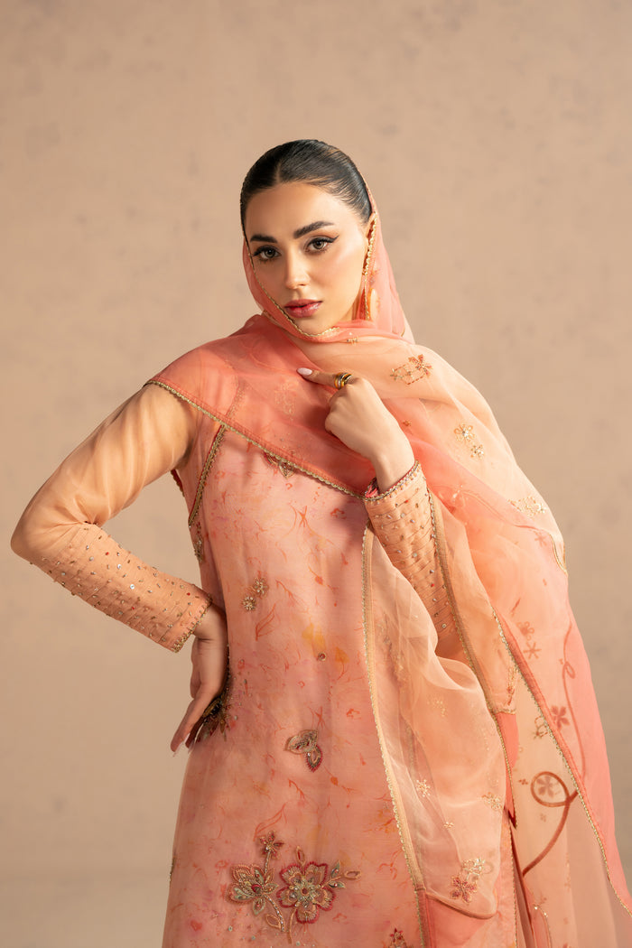 Portrait close view highlighting neckline adda work and soft carrot peach shade, complete occasion ready stitched outfit.