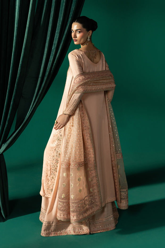 Side view of Azba showing the peach A-line frock, wide flared sharara and embroidered Organza Barosha dupatta.