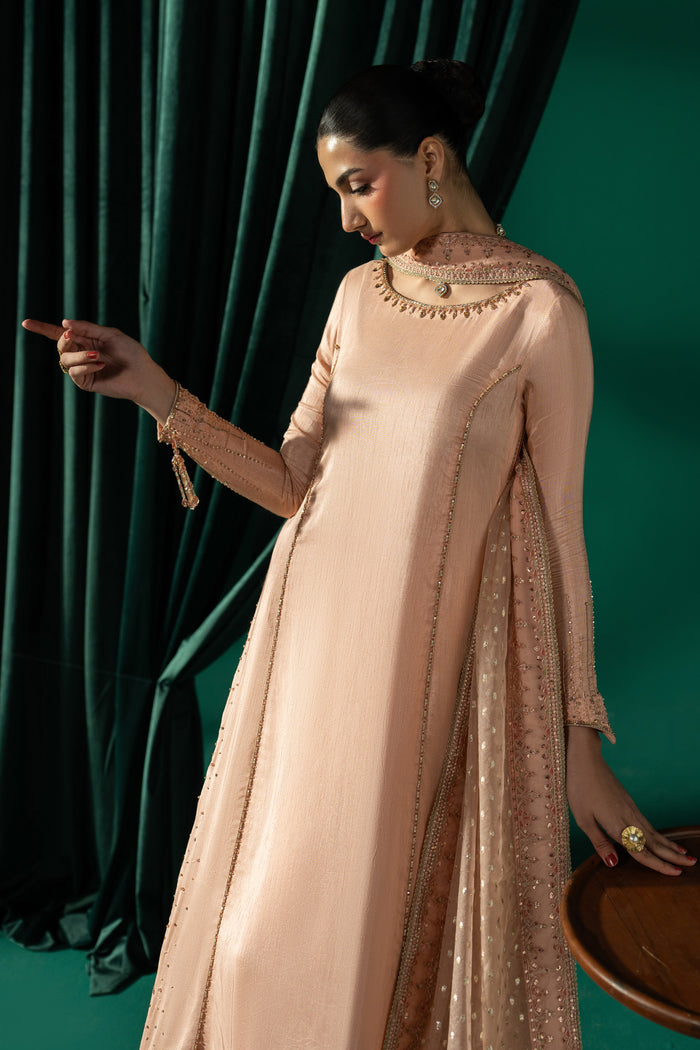 Three-quarter view of Azba highlighting the long peach frock, side-open silhouette and flowing embroidered dupatta.