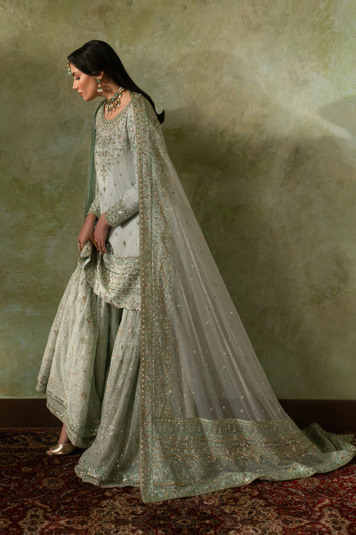 Side view of Azeyma pistachio Nikkah dress with flowing net sharara flare and soft dupatta fall, modest and elegant ready made bridal formal outfit.