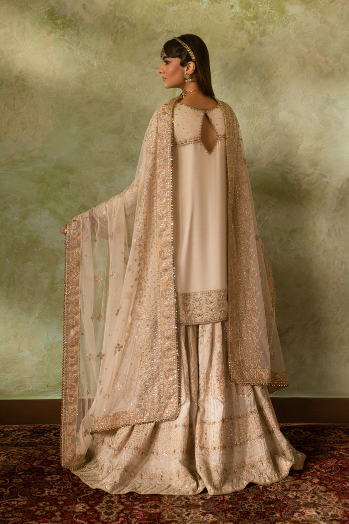 Back view of Damiya off white Nikkah dress showing smooth fall of silk shirt and wide sharara flare with light net dupatta, elegant ready made bridal formal outfit.