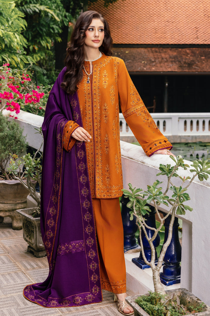 Woman wearing an orange embroidered outfit with a purple dupatta in a garden setting.