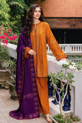 Woman wearing an orange embroidered outfit with a purple dupatta in a garden setting.