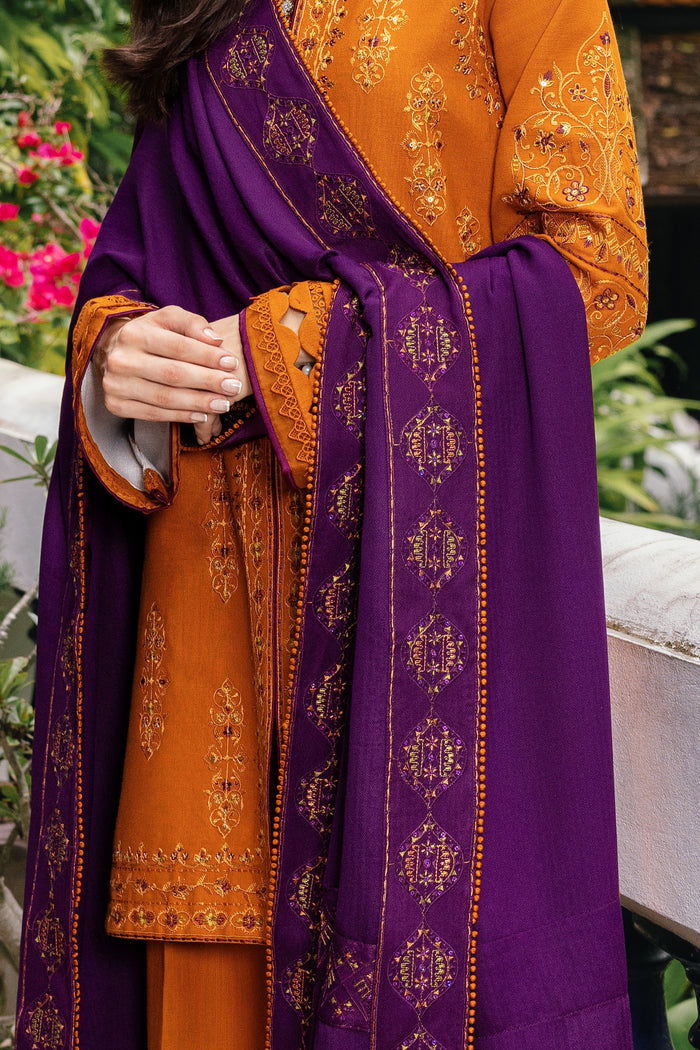 Orange traditional outfit with purple dupatta featuring intricate patterns, held by a person.