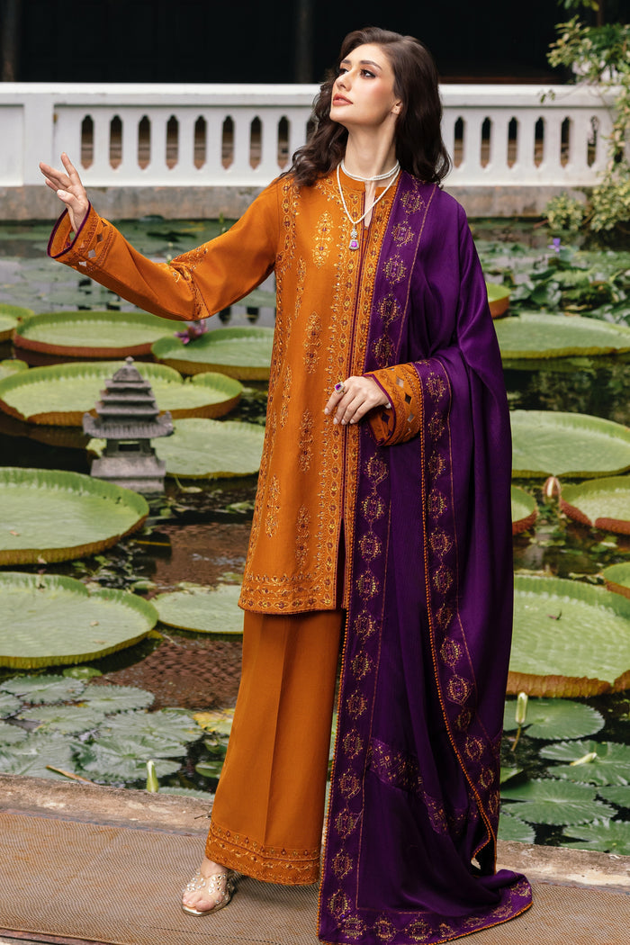 Woman in traditional orange and purple outfit standing by a pond with lily pads.