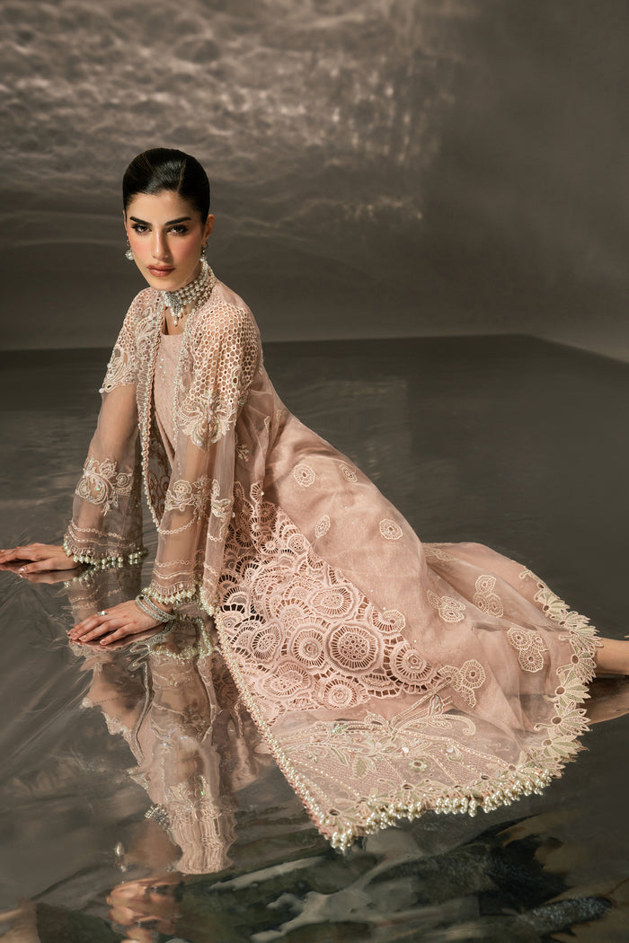 Seated side view of Farfalle showing the light peach Organza gown with layered embroidered panels and flowing hem.