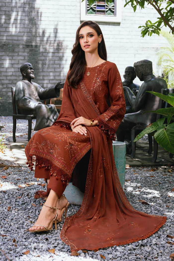 Seated pose of model wearing NAQSHI Farukh rust brown embroidered outfit highlighting fabric fall and elegant overall look