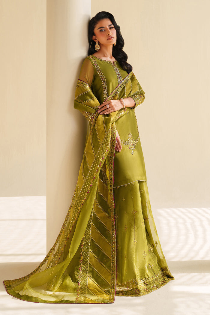 Woman wearing a green saree with intricate patterns against a neutral background.