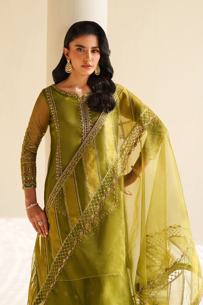 Woman wearing a green traditional outfit with a dupatta against a neutral background.