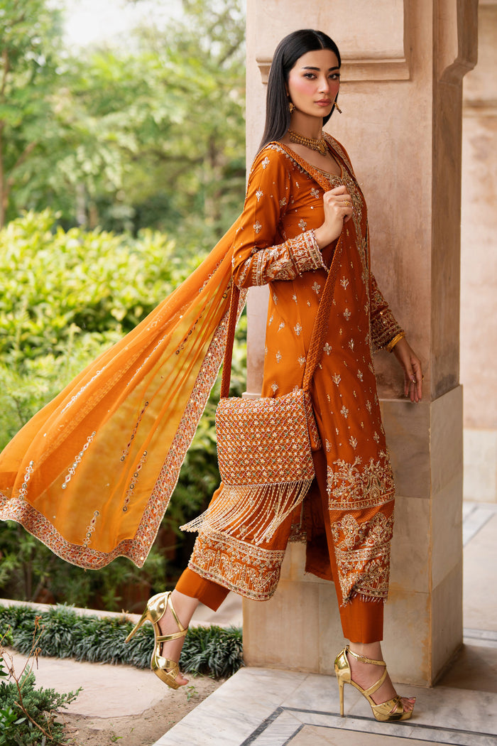 NAQSHI rust formal ready-to-wear gown in Indian raw silk shown in side pose, featuring detailed sleeve borders, flowing chiffon dupatta, and elegant mid-calf length silhouette.
