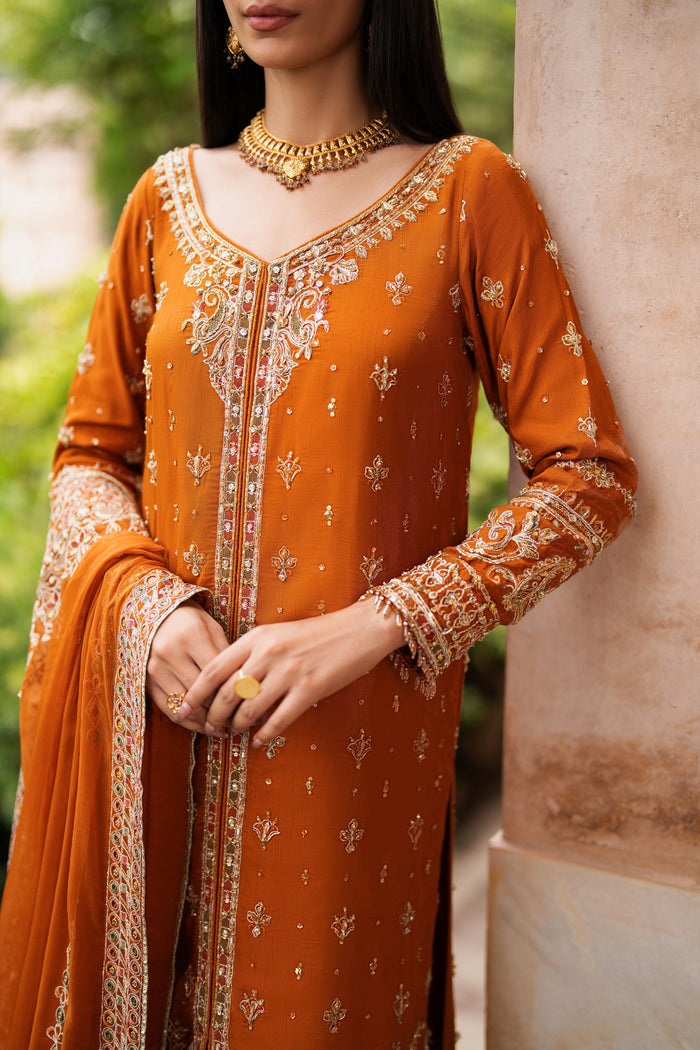 Close-up of rust Indian raw silk formal gown by NAQSHI highlighting neckline embroidery, fine adda work, sequin detailing, and neat stitching on the front panel.
