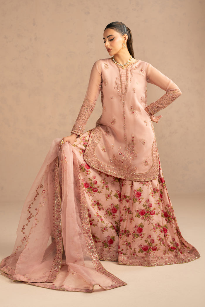 Seated pose showing full sharara flare and soft drape of embroidered organza dupatta.