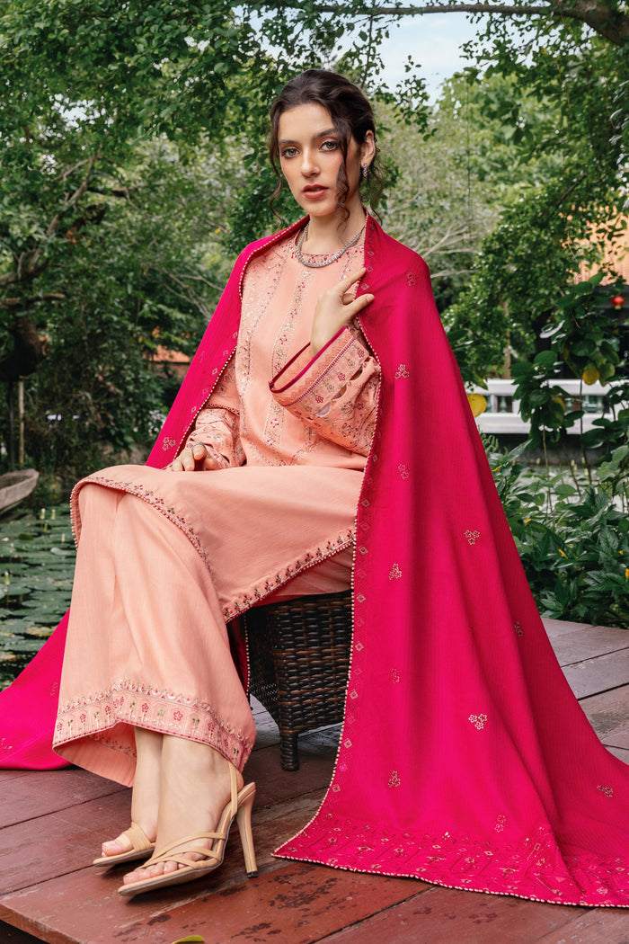 Woman in a peach traditional outfit with a pink dupatta sitting outdoors.