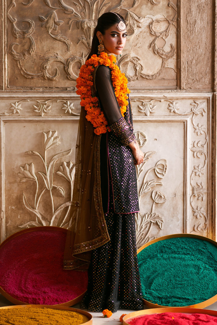 Side profile of Irra black crinkle dress featuring flary trousers, embellished sleeves and brown contrast festive styling