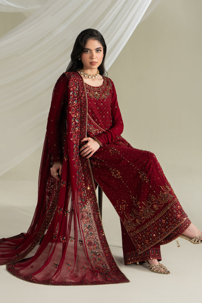 Deep red formal ready-to-wear outfit with flared shirt, culotte, and dupatta, seated pose showing fabric flow and styling