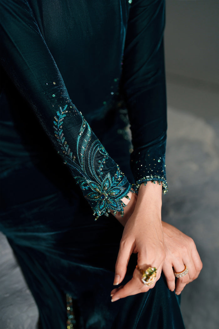 Close-up of a person wearing a dark green dress with intricate patterns and holding hands.