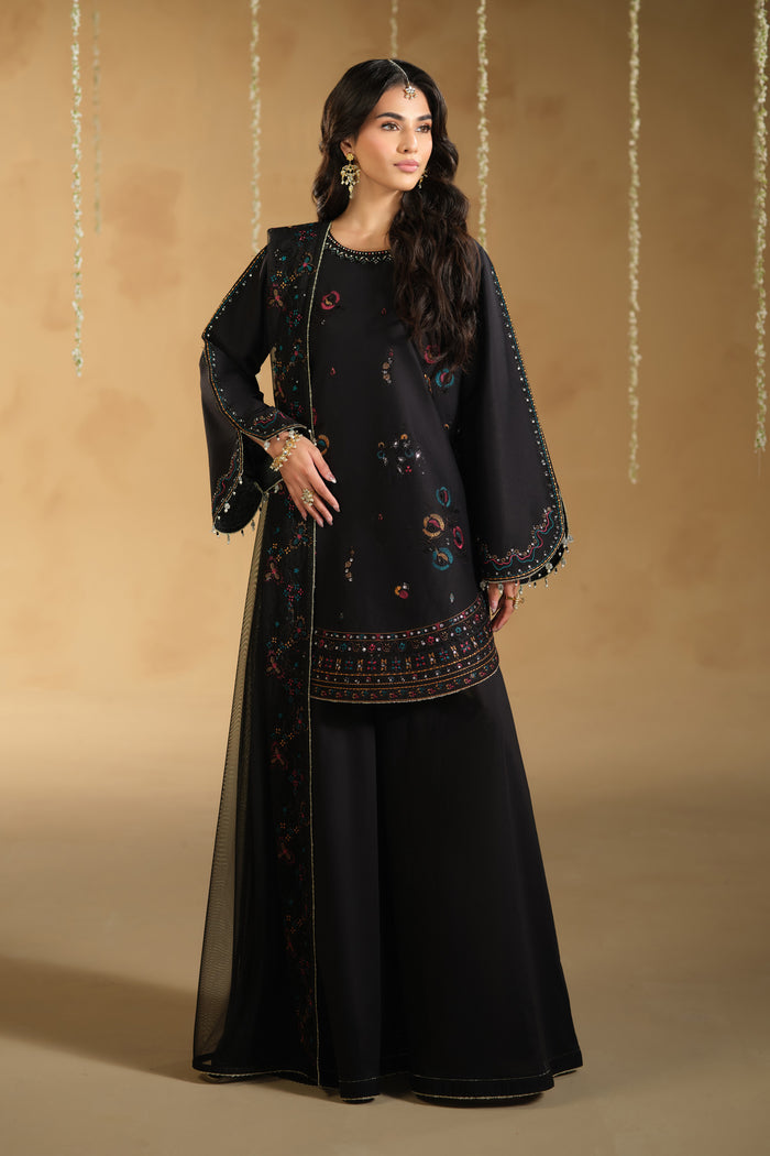 Full length standing pose of Lael ready to wear black outfit highlighting embroidered borders and balanced flare pants