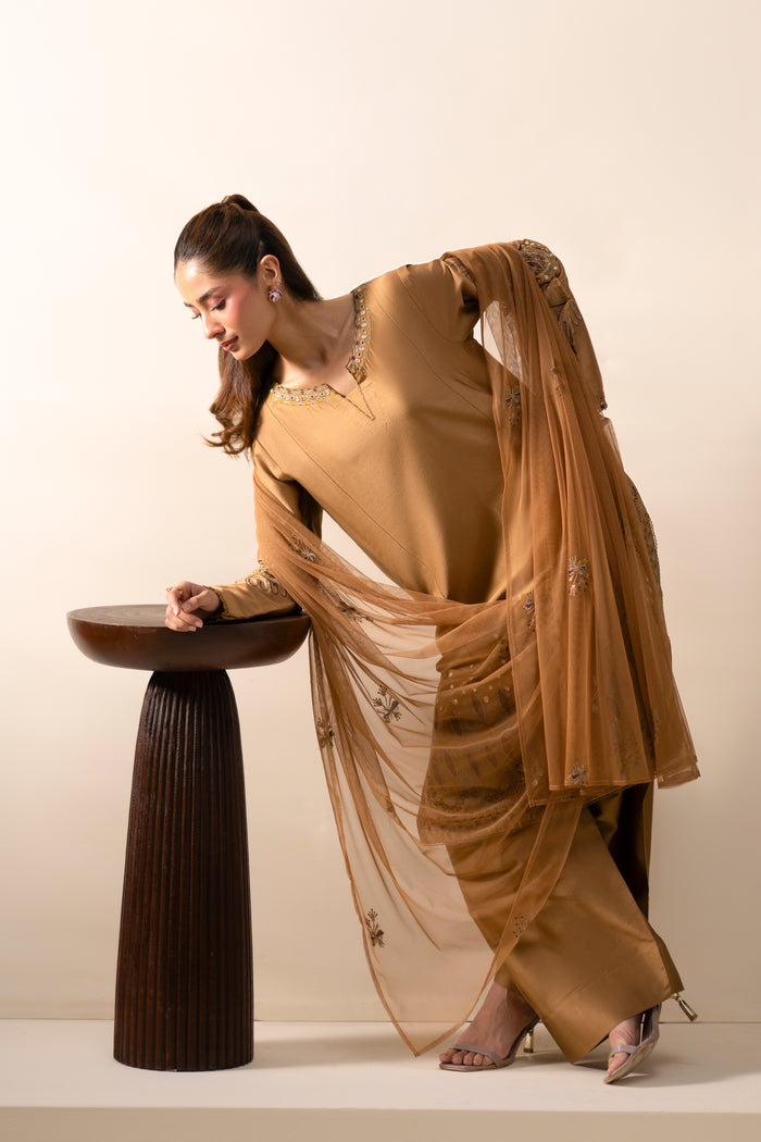 Maddox Golden Brown outfit styled in motion with embroidered shirt, shalwar and flowing Net dupatta.