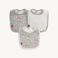 A three-pack of baby bibs featuring one solid white bib with a light gray border and two bibs with a repeating print of white sheep on a light gray background, By Magnetic Me.