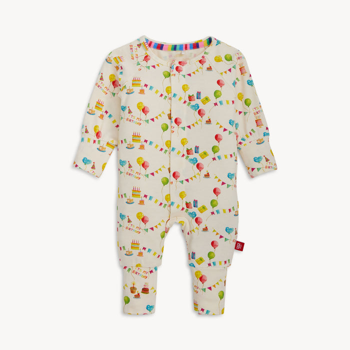 A cream-colored long-sleeved convertible coverall with a watercolor "It's My Birthday" print and hidden magnetic closures that easily swap between footed and footless styles, by Magnetic Me.