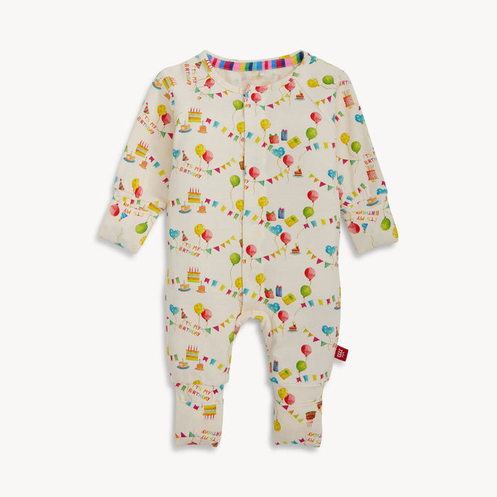 A cream-colored long-sleeved convertible coverall with a watercolor "It's My Birthday" print and hidden magnetic closures that easily swap between footed and footless styles, by Magnetic Me.