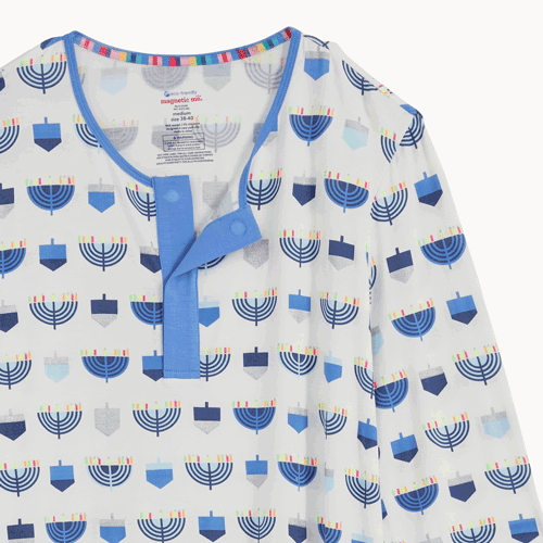 Open and close magnet on the top of A two-piece men's pajama set in white fabric featuring a long-sleeve top with hidden magnets and matching joggers, both detailed with an all-over print of blue and silver dreidels and menorahs, by Magnetic Me.