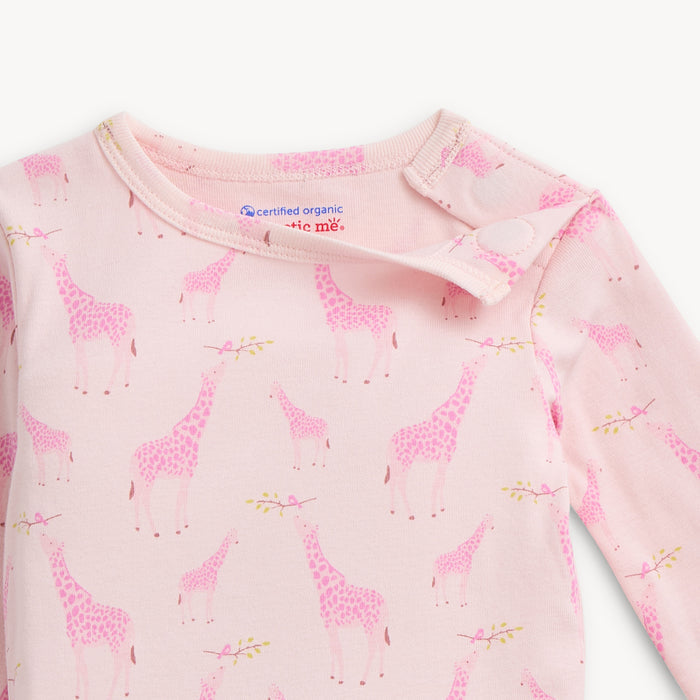 Open magnet on the shoulder of A light pink long-sleeve pajama set featuring an all-over Jolie Giraffe print of pink-toned giraffes and small storks on leafy branches, by Magnetic Me.
