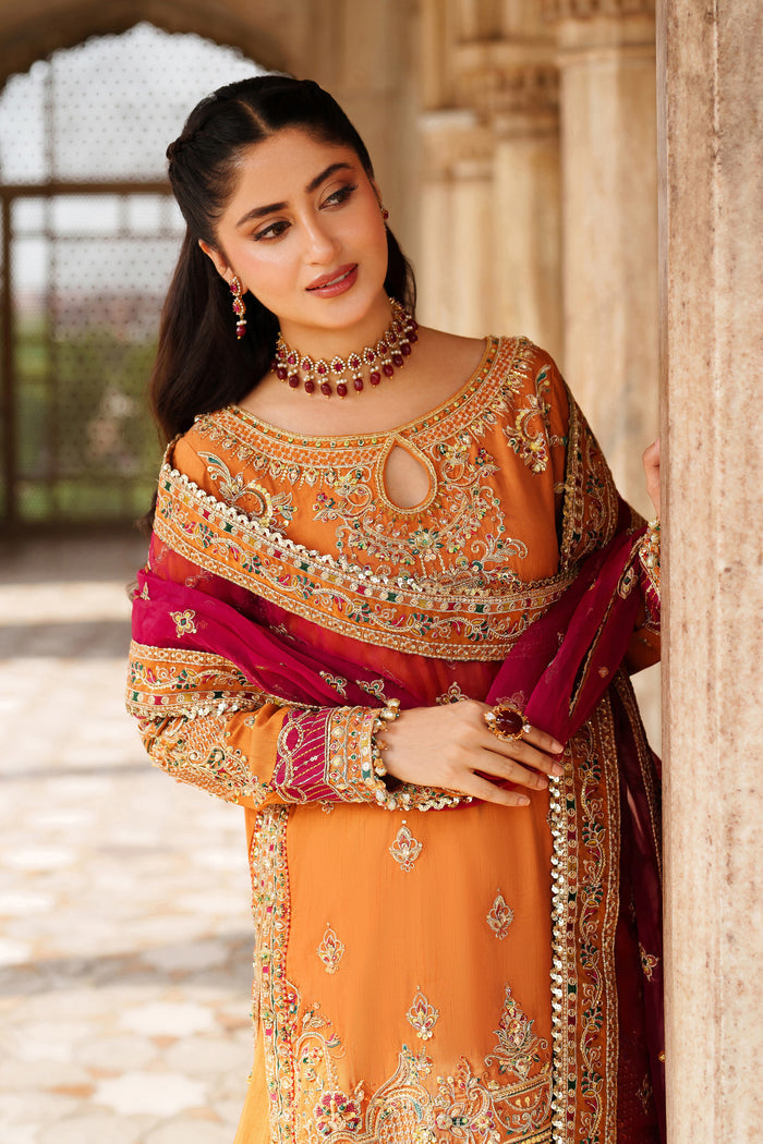 Styled close-up shot of NAQSHI Mahzaeeb orange embroidered formal outfit with decorative neck and shoulder details for festive events.
