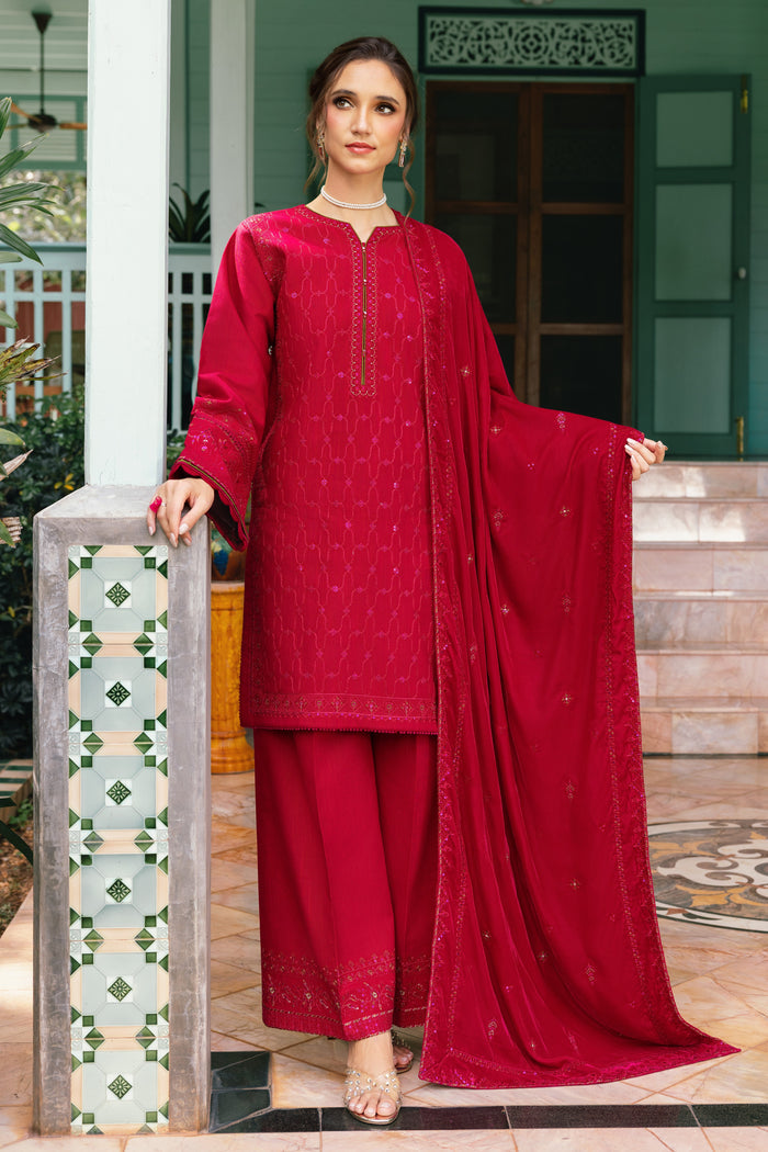 Woman in a red traditional outfit standing in front of a decorative wall.