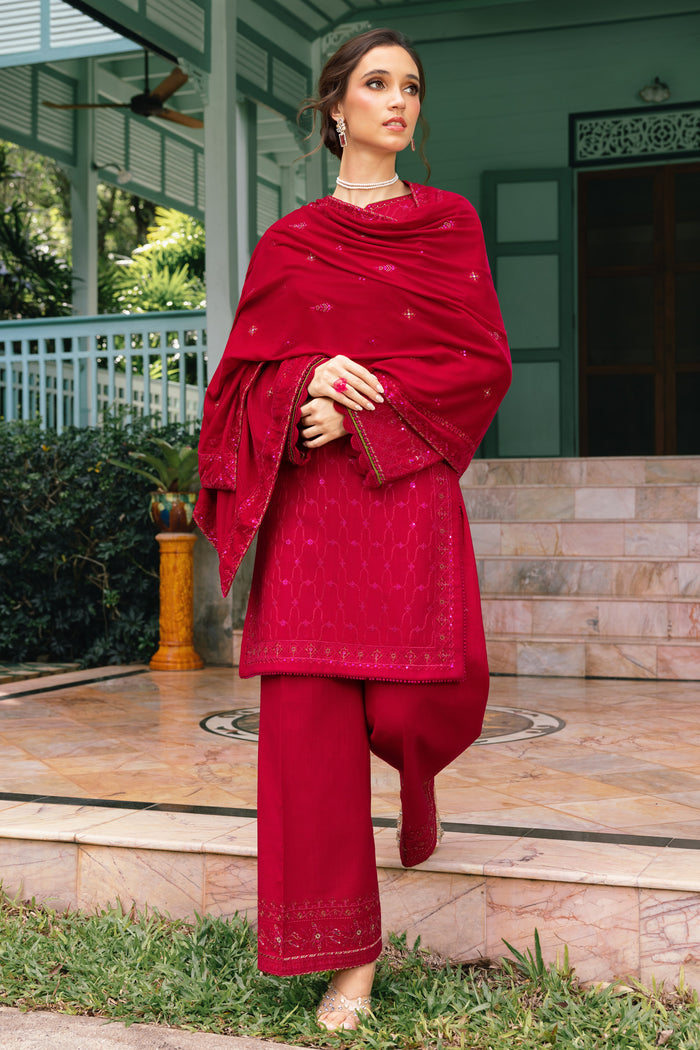 Woman wearing a red traditional outfit standing outdoors.