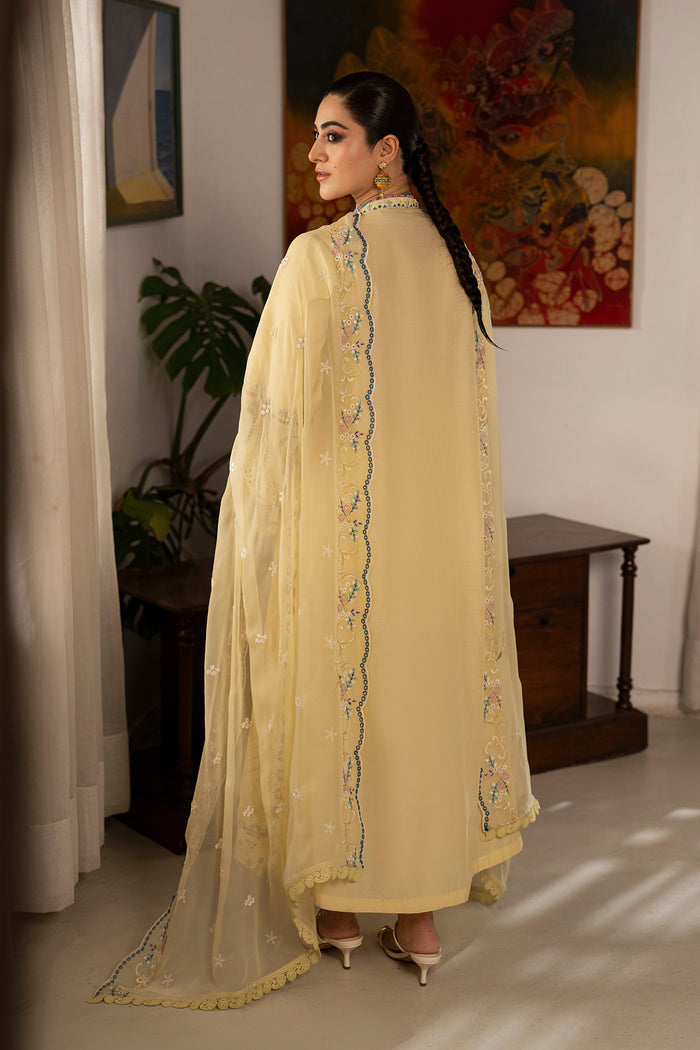 Side view of Nashiman light yellow embroidered lawn suit featuring long flowy silhouette, embroidered panels and crinkle dupatta with decorative borders