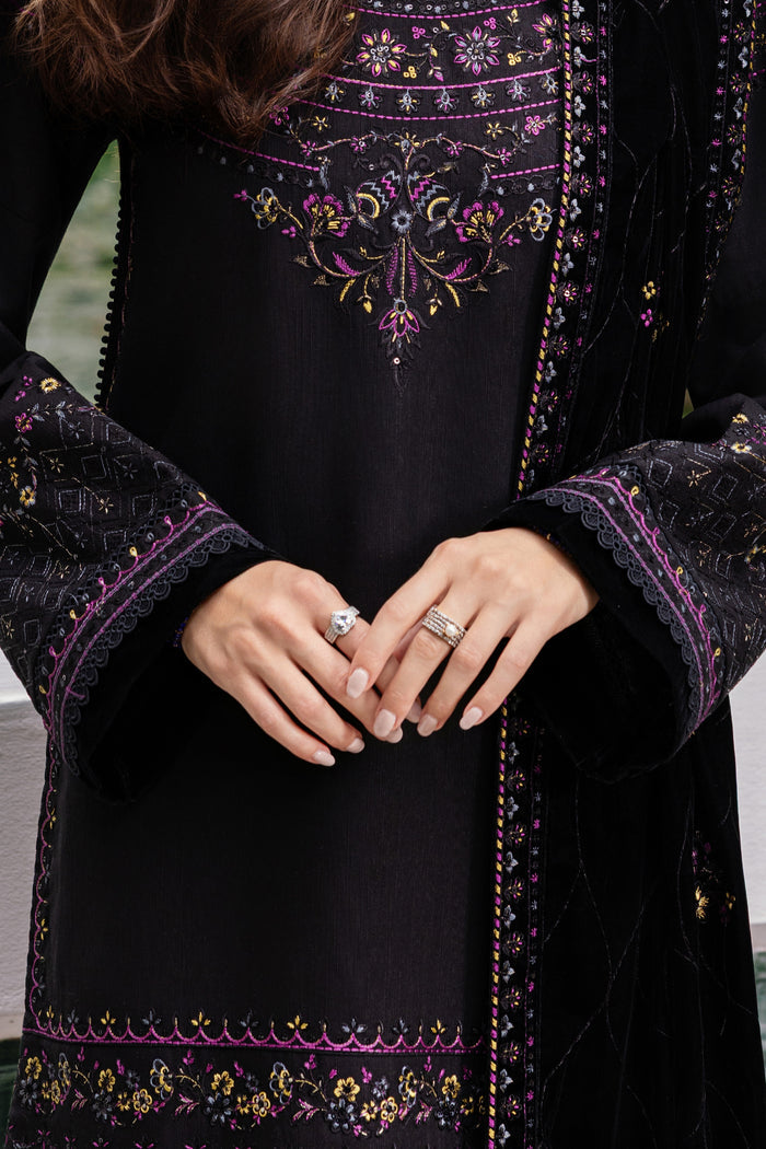 Black embroidered garment with purple and gold details, worn by a person.
