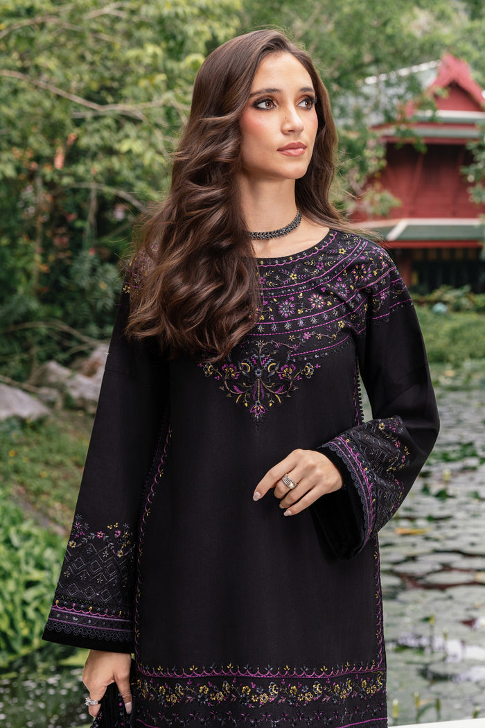 Woman wearing a black embroidered dress with a scenic background