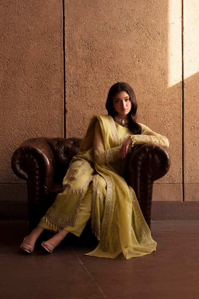 Seated pose of NAQSHI Pedro lime green 3-piece formal outfit with embroidered khadi net shirt, raw silk trousers and embroidered dupatta