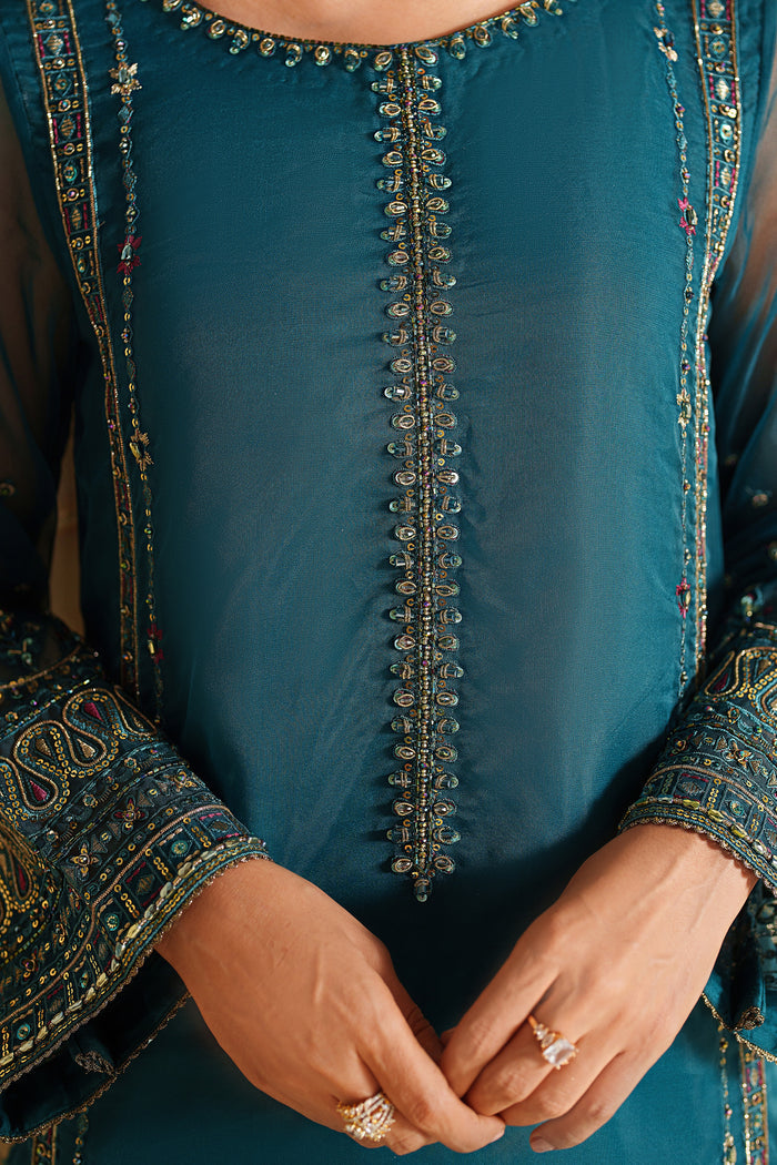 Close-up of NAQSHI deep teal dress showing detailed embroidery on the front panel and neckline