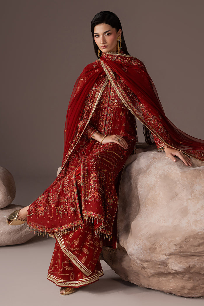 Seated view of Rayaleen rust orange semi-formal outfit showing the embroidered gown, flared pants and draped Net dupatta.