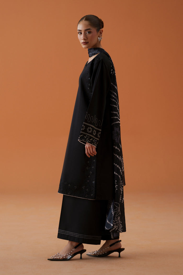 Side view of Riedel black ready-to-wear dress showing embroidered lawn shirt, relaxed sleeves, culotte trouser, and printed chiffon dupatta.