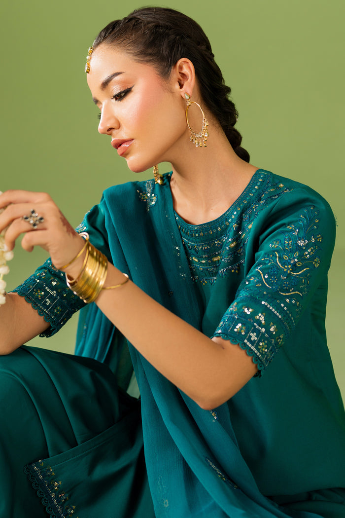 Close-up of NAQSHI Ruhab outfit showing sleeve embroidery, neckline detail, and smooth zinc green fabric