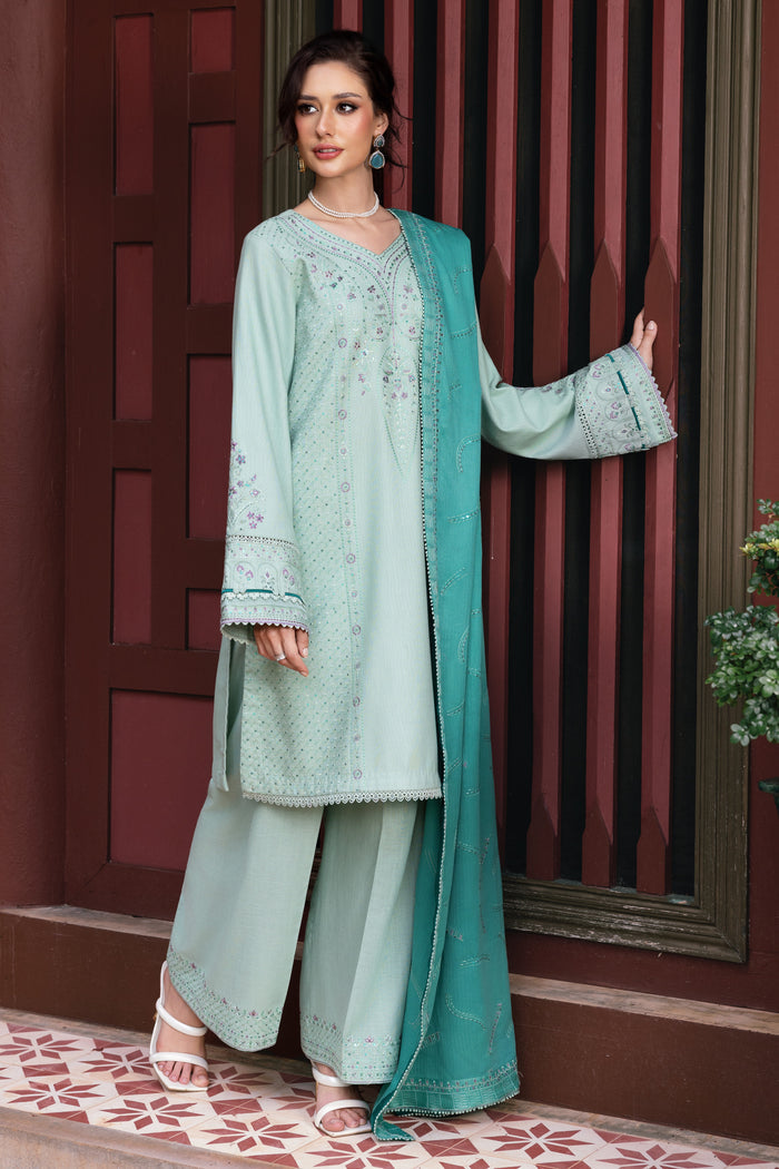 Woman in a light green traditional outfit with a matching dupatta against a red and brown background.