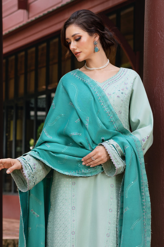 Woman wearing a teal and light green traditional outfit with a matching shawl.