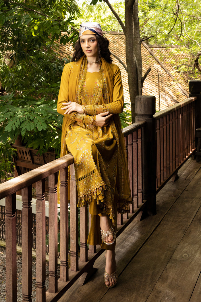 Woman in a yellow dress standing on a wooden deck with greenery in the background