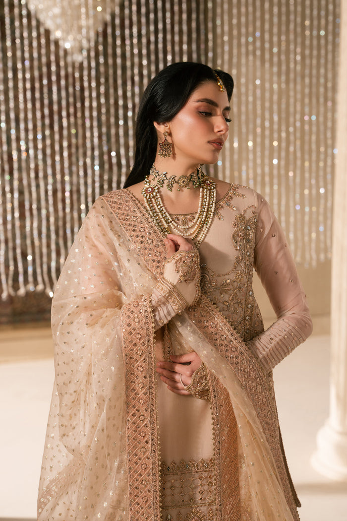 Side pose of Tizmat Nikkah dress showing soft peach tone, balanced silhouette, flared garara fall and lightweight organza dupatta, graceful ready to wear wedding outfit.
