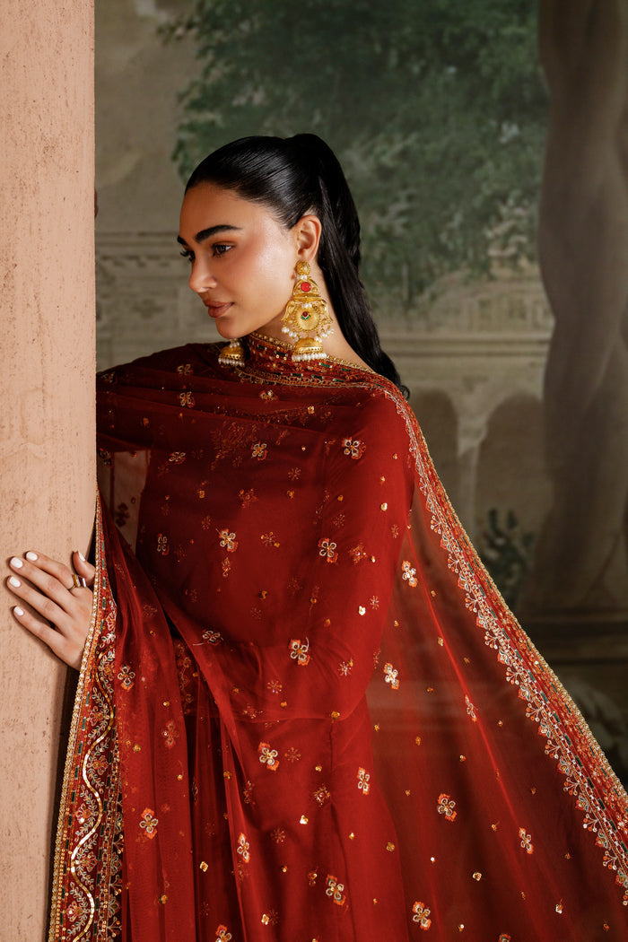 Portrait of model in NAQSHI Vaneeza rust velvet 3-piece sharara outfit with detailed sequin embroidery and silk finish — premium event dress