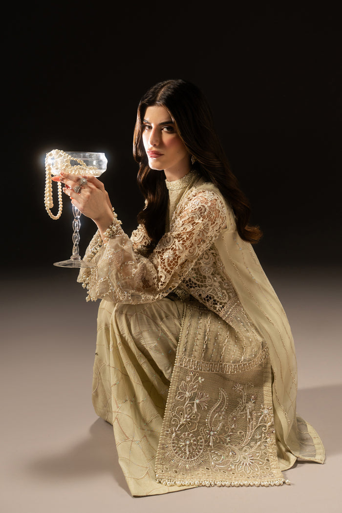 Seated view of Varena showing the embroidered off-white Organza shirt, layered hem and flowing wide flare pants.