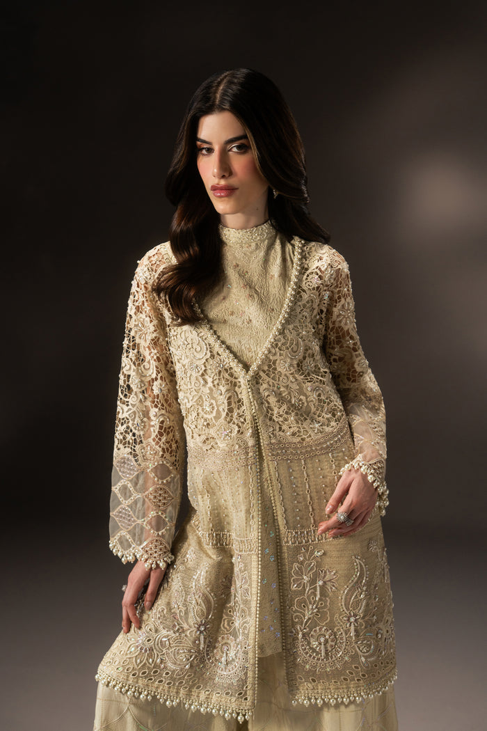 Front three-quarter view of Varena off-white evening wear showing the layered shirt, side slit and coordinated wide flare pants.